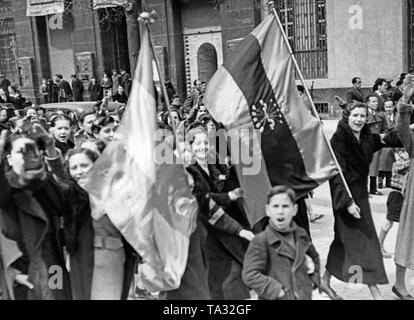 Partisans du général Franco à pied à travers les rues de Madrid à la fin de mars après l'entrée des troupes de Franco, le 28 mars 1939. La montée des femmes dans le bras droit, sur le salut fasciste-rouge du drapeau bleu à l'avant sont le joug et les Flèches comme le symbole du parti fasciste (Falange Espanola Tradicionalista de las JONS). Banque D'Images