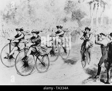 Photo d'une course cycliste féminine à Paris. Sur l'écran, quatre jeunes femmes équitation dans la rue. Sur le côté gauche et côté droit de la route sont spectateurs. Banque D'Images