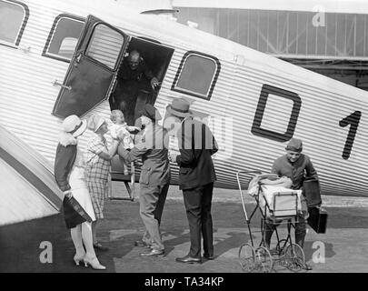 Trois gardiens de la Lufthansa aider une jeune famille obtenir sur un Junkers G24. Banque D'Images