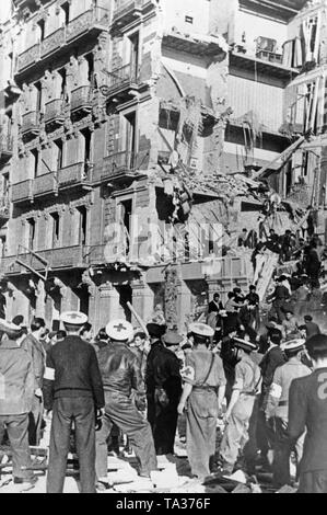 Photo d'un partiellement détruit sept étages à la Plaza de Catalunya à Barcelone après une attaque à la bombe par la Force aérienne nationale espagnole le 19 mars 1938. Les civils et les secouristes tentent de récupérer les survivants des décombres. Banque D'Images