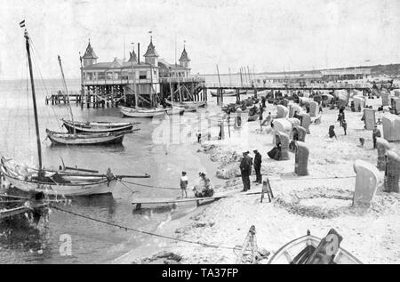 La jetée de la station balnéaire d'Ahlbeck, Heringsdorf sur l'île d'Usedom. Sur la plage sont les bateaux de pêche. Les baigneurs peuvent se protéger du soleil dans des chaises de plage. Banque D'Images