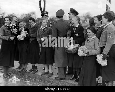 Les filles de la BDM saluer les soldats de la Luftwaffe comme ils mars avec des fleurs. Ils construire un aérodrome militaire avec l'école de pilote de chasse dans la région de Werneuchen qui est devenue une garnison. Banque D'Images