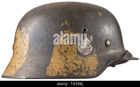 Un casque d'acier M 35 avec début de la peinture de camouflage les deux emblèmes de l'acier crâne avec bi-couleur de la peinture de camouflage vert pomme sur la couche de base, l'emblème de l'aigle jusqu'à 85 % et la protection nationale environ 40  % intact. L'intérieur avec bouilloire stamping 'ET66' (Thale Iron Works) et '4882'. Revêtement intérieur complet avec jugulaire historique., historique, armée, armées, forces armées, militaires, militaria, objet, objets, alambics, clipping, coupures, découper, découpage, cut-outs, 20e siècle, Editorial-Use-seulement Banque D'Images