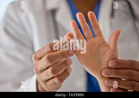 Médecin examinant les mains d'un jeune patient. Banque D'Images