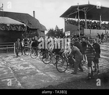 Les participants d'une course de cyclisme sur piste sont prêts à commencer la compétition dans le Volksgarten Nymphenburg, Munich, en juin 1898. Dans l'arrière-plan, une tribune. Banque D'Images