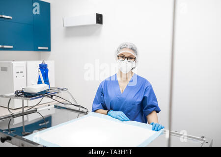 Dark-eyed vet portant des lunettes en uniforme avant chirurgie Banque D'Images