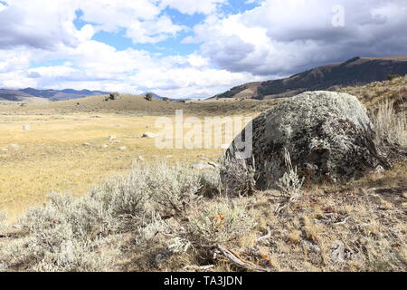 Couverts de lichen rocher sur le bord d'une colline à la recherche sur une dépression dans le terrain rempli d'une dispersion des rochers plus Banque D'Images