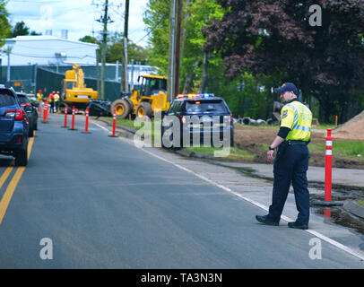 Cromwell, CT USA. Mai 2019. Un jeune agent de police avec l'écoute à l'exploitation d'écouteurs peut-être que ses morceaux préférés tout en dirigeant le trafic de détour. Banque D'Images