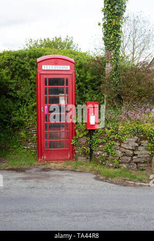 Une boîte de téléphone rouge traditionnelle britannique et lampe style boîte postale dans un cadre rural à Cornwall Banque D'Images