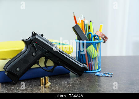 Pistolet et papeterie sur table en classe. Pas d'armes à l'école Banque D'Images