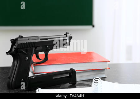 Pistolet et papeterie sur table en classe. Pas d'armes à l'école Banque D'Images