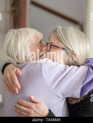 Après une visite pour voir sa vieille mère & malvoyants,la fille des étreintes et dit au revoir à sa mère, avant son long voyage de retour. Banque D'Images