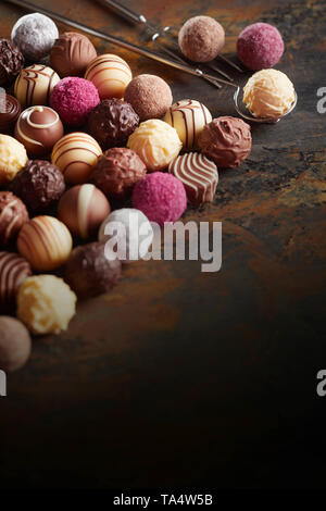 Chocolat pralines de luxe dans neat lignes diagonales disposées sur rustique en bois foncé avec corner espace copie en format vertical Banque D'Images