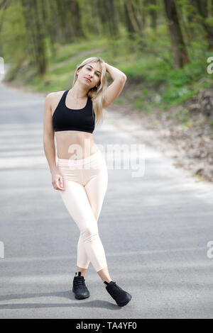 Une jeune femme blonde, sympathique est activement passer du temps à l'extérieur. La fille est vêtue de vêtements sport. Banque D'Images