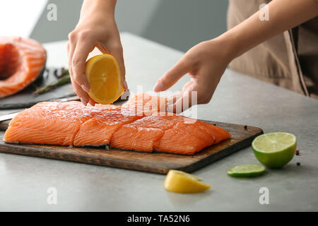 Woman squeezing jus de citron sur le filet de saumon Banque D'Images