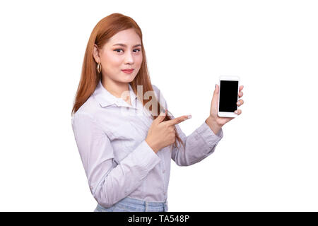 Smiling Asian Woman in casual shirt holding mobile phone et pointant sur smartphone isolé sur fond blanc avec clipping path Banque D'Images