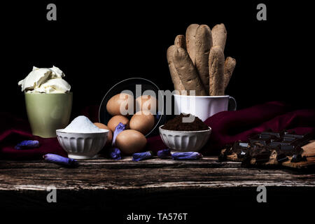 Ingrédients pour tiramisu italien, chocolat, café et mascarpone sur fond noir Banque D'Images