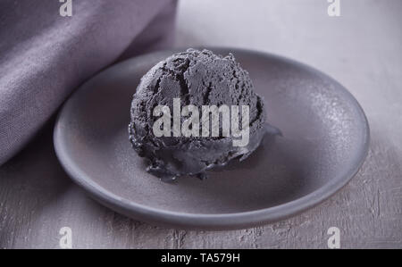 La nourriture à la mode. Black Ice cream sur une plaque en céramique noir gris avec une serviette sur le tableau gris. Le minimalisme. Banque D'Images