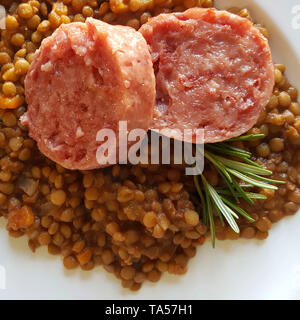 Repas du Nouvel An de style italien. Vue de dessus deux tranches de cotechino (saucisse de porc), de lentilles et de romarin sur plaque blanche. Vue d'en haut Banque D'Images
