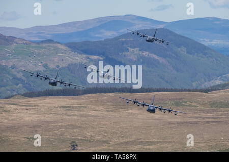 Un rare groupe de quatre avions Hercules C-130 de l'USAF voler à basse altitude dans la zone 7, boucle Mach près de Dolgellau, Pays de Galles, Royaume-Uni. Banque D'Images