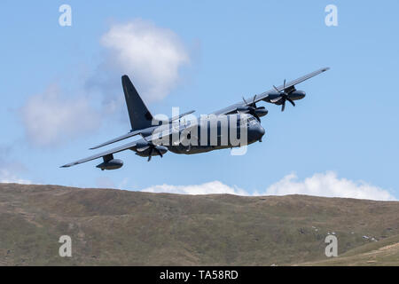 Un rare groupe de quatre avions Hercules C-130 de l'USAF voler à basse altitude dans la zone 7, boucle Mach près de Dolgellau, Pays de Galles, Royaume-Uni. Banque D'Images