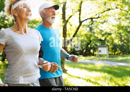 Happy fit senior couple exercising in park Banque D'Images