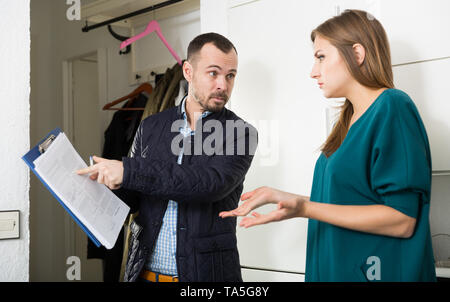 Portrait de jeune femme frustrée de parler à recouvrement lui rendre visite à la maison et exigeant de payer ses dettes Banque D'Images