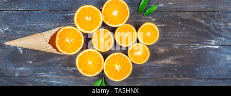 Plat à l'obscurité créative jeter Vue de dessus des tranches de fruits d'orange dans la crème glacée cornet gaufré sur fond de table en bois brun avec copie espace. Un minimum de Banque D'Images