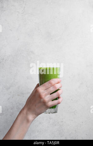 Smoothie vert dans la main. Femme hand holding glass of green Smoothie Détox épinards, copiez l'espace. Banque D'Images