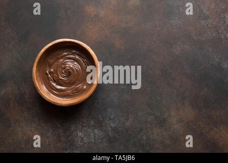 Pâte à tartiner au chocolat sur fond sombre, vue du dessus, copiez l'espace. Du chocolat fondu dans un bol. Banque D'Images