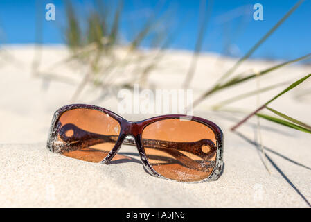 Fond d'été avec accessoire de vacances sur la plage, lunettes de soleil sur les dunes de sable et de ciel bleu. Maison de vacances loisirs concept. Banque D'Images