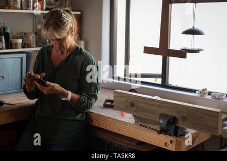 Female carpenter using mobile phone in workshop Banque D'Images