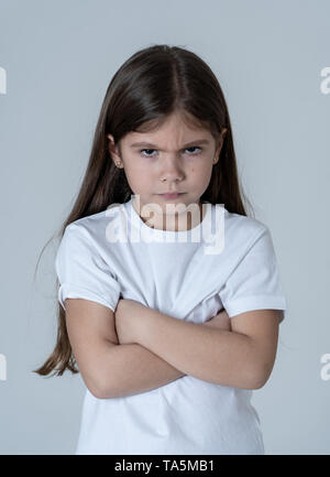 Portrait of a cute pretty girl enfant en colère et déçu avec ses bras croisés. Isolé sur fond neutre. Chez les enfants de sentiments et être Banque D'Images