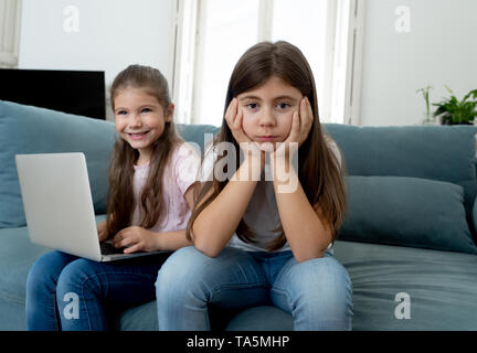 Frère ou sœur plus jeune en colère à passer trop de temps en ligne en utilisant l'ordinateur portable. La technologie numérique accro kid jouer avec l'ordinateur l'ignorant triste vieille Banque D'Images