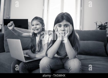 Frère ou sœur plus jeune en colère à passer trop de temps en ligne en utilisant l'ordinateur portable. La technologie numérique accro kid jouer avec l'ordinateur l'ignorant triste vieille Banque D'Images