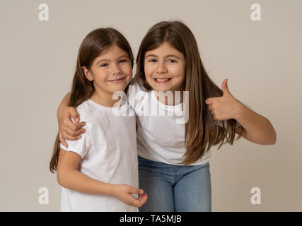 Joli portrait de deux frères soeurs filles gaie de s'amuser ensemble hugging and laughing posant pour la caméra. Studio shot with copy space. En F Banque D'Images