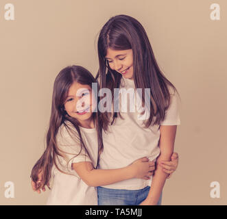 Joli portrait de deux frères soeurs filles gaie de s'amuser ensemble hugging and laughing posant pour la caméra. Studio shot with copy space. En F Banque D'Images