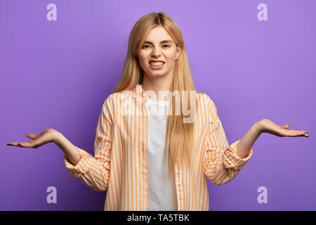 En colère irrité femme portant chemise rayée et T-shirt isolés sur fond bleu, haussant les épaules, isolé sur fond bleu. studio Banque D'Images