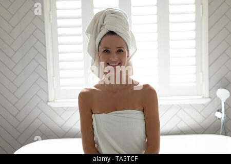 Femme assise sur le bord de la baignoire dans la salle de bains Banque D'Images