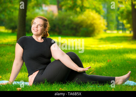 Une assurance femme de taille moyenne dans le parc faisant du yoga tôt le matin sur la pelouse Banque D'Images