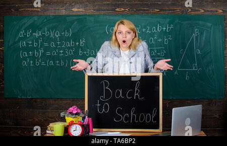 L'école. L'enseignement à domicile. surpris femme. Retour à l'école. Journée des enseignants. enseignant avec réveil au tableau noir. Le temps. femme en classe. L'étude et l'éducation. L'école moderne. Jour des connaissances. Regardez ceci. Banque D'Images