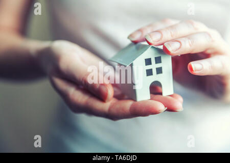 Female woman hands holding petit blanc miniature toy house. L'assurance des biens hypothécaires dream déménagement accueil concept et de l'immobilier Banque D'Images