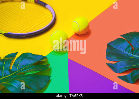 Mise en page avec Tennis balles de tennis, raquette et feuilles de monstera tropicaux multicolores sur fond abstrait autre néon. Banque D'Images