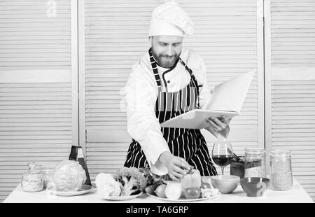 Livre des recettes de famille. Guide de cuisson ultime pour les débutants. Selon recette. Chef barbu homme à la cuisson des aliments. Guy lire livre de recettes. Concept d'arts culinaires. Apprendre l'homme recette. Améliorer les compétences de cuisson. Banque D'Images