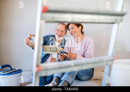 Young couple lorsque selfies peinture des murs dans la nouvelle maison, réinstallation concept. Banque D'Images