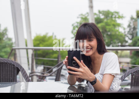 Happy asian woman holding smart phone in coffee shop Banque D'Images