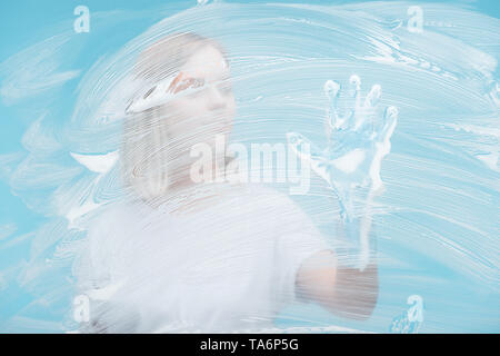 Portrait de jeune femme au gant de caoutchouc mousse recouvert de verre toucher sur fond bleu Banque D'Images