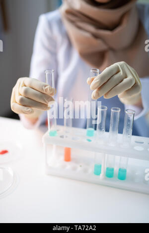 Close up du chimiste dans les gants en tubes à essai avec des produits chimiques Banque D'Images