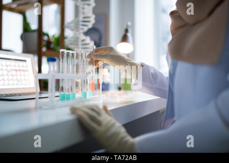 Chimiste vêtu de blanc manteau et gants de travail au laboratoire Banque D'Images