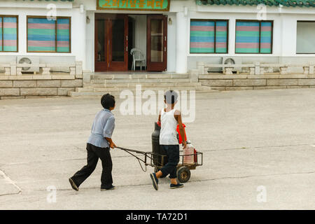 Kaesong, Korea-July Nord 30, 2014 : femme de la Corée du Nord avec un garçon sur un chariot porte un baril d'eau. Banque D'Images